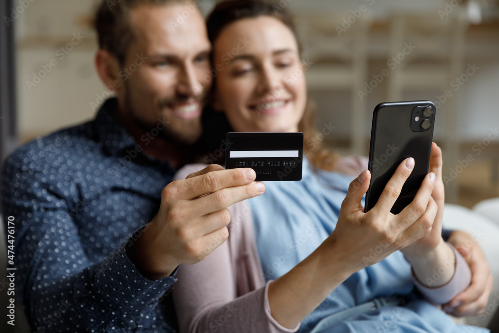 Smartphone and credit card in cheerful couple hands close up. Happy dating man and woman using online ecommerce, banking app on mobile phone for shopping on internet, payments for purchase