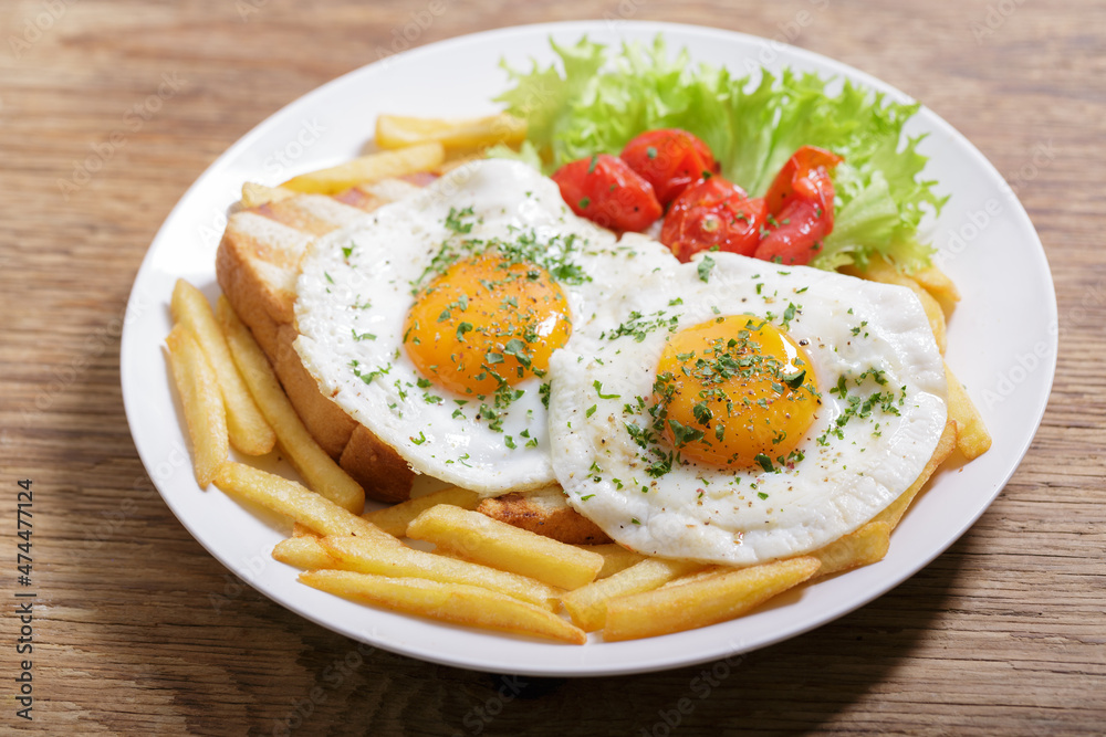 Breakfast with plate of fried eggs, toasts and french fries Breakfast with plate of fried eggs, toasts and french fries