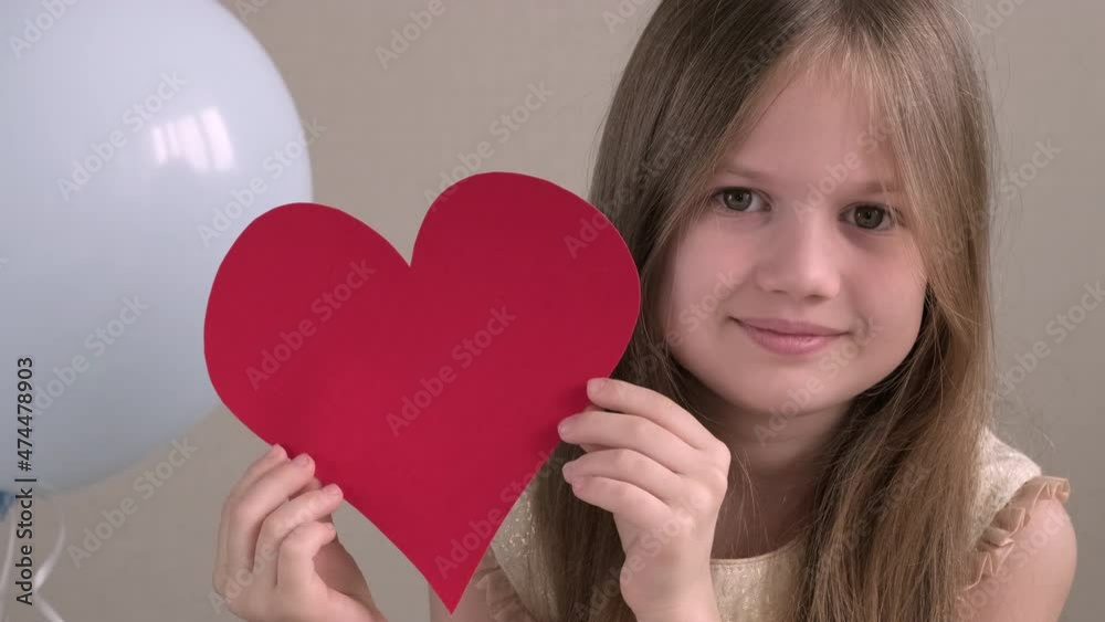 Close up portrait of cute little girl holding big red heart on background of air balloons. Valentines Day, love, mothers Day, romantic concept. Adorable kid smiling. Close up portrait of cute little girl holding big red heart on background of air balloons. Valentines Day, love, mothers Day, romantic concept. Adorable kid smiling.