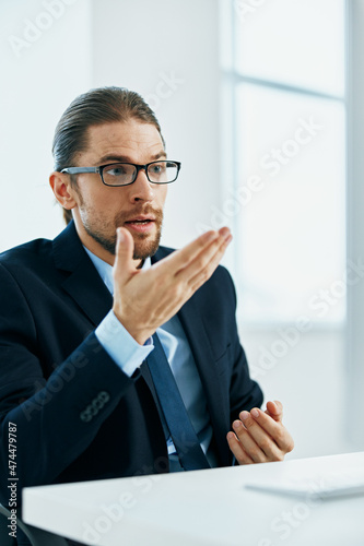 a man in a suit with glasses typing at his desk