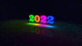 2022 new year bright text with neon glowing effect isolated on black stars burst particle background.