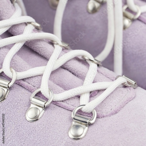 Light lilac suede hiker boots with metal eyelets and lacing with white laces close up