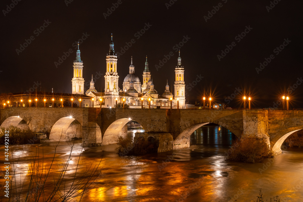 Long exposure at night on the Puente de Piedra next to the Basilica of Nuestra Señora del Pilar on the Ebro river in the city of Zaragoza, Aragon. Spain