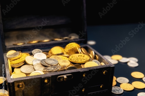 Heap of coins in small wooden chest