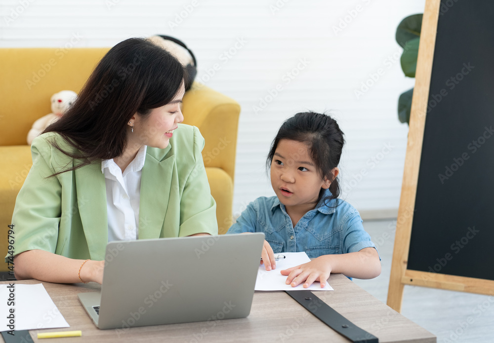 Young Asian Mother Teaching Her Child to Do Homework in Living Room. Homeschooling Concept Young Asian Mother Teaching Her Child to Do Homework in Living Room. Homeschooling Concept