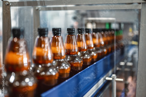 Plastic bottles with light filtered beer on the conveyor. Industrial production of beer.