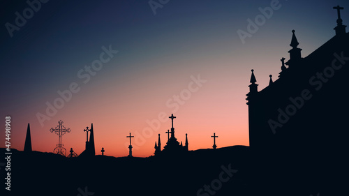 Silhouettes of crosses in a twilight cemetery.