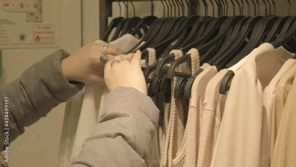 a young brunette with a beautiful manicure chooses clothes in a boutique