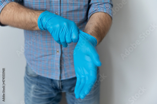 Close up midsection view man wear medical protective rubber gloves, on gray studio background. Preventive measures due COVID-19 pandemic outbreak. Self-care, personal safety, stop corona virus concept