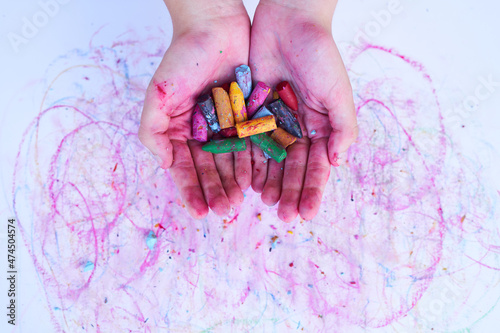 Φωτογραφία Multicolored worn wax crayon on two hands on a smudged white paper background