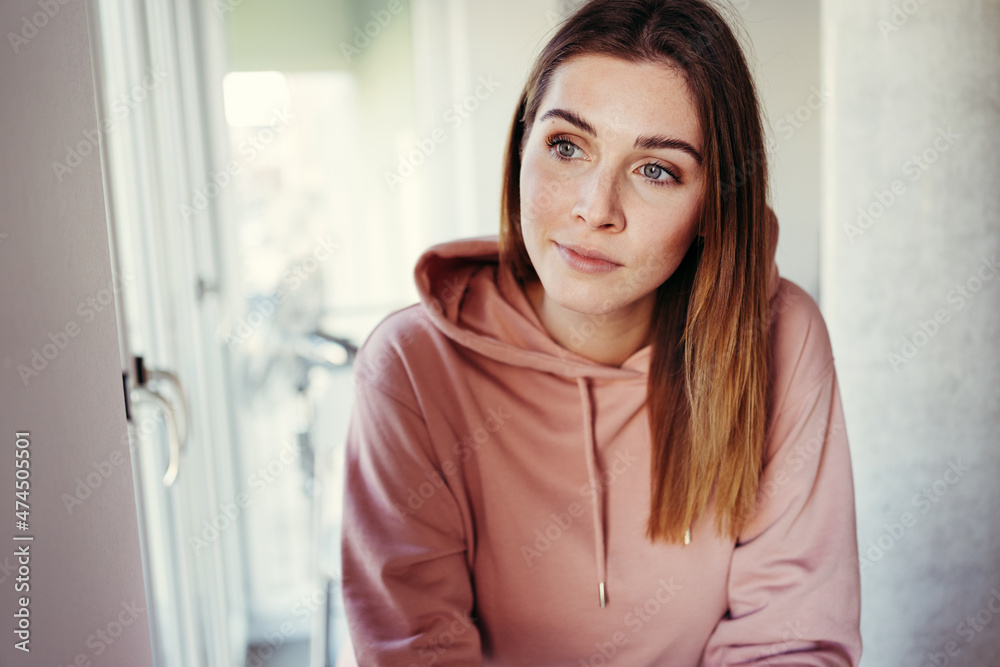 Young woman sitting daydreaming with a faraway expression Young woman sitting daydreaming with a faraway expression
