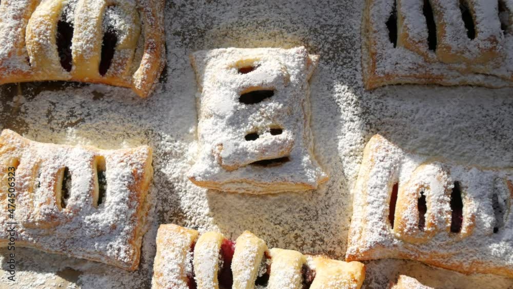 Delicious homemade cakes. Puff pastry with cherries, generously sprinkled with icing sugar on top. Delicious fresh buns close up view Delicious homemade cakes. Puff pastry with cherries, generously sprinkled with icing sugar on top. Delicious fresh buns close up view