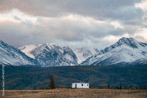 Round yurt in the autumn steppe against the background of snow-capped mountains