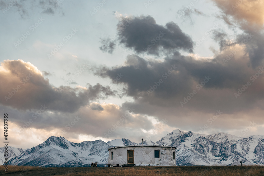 Round yurt in the autumn steppe against the background of snow-capped mountains