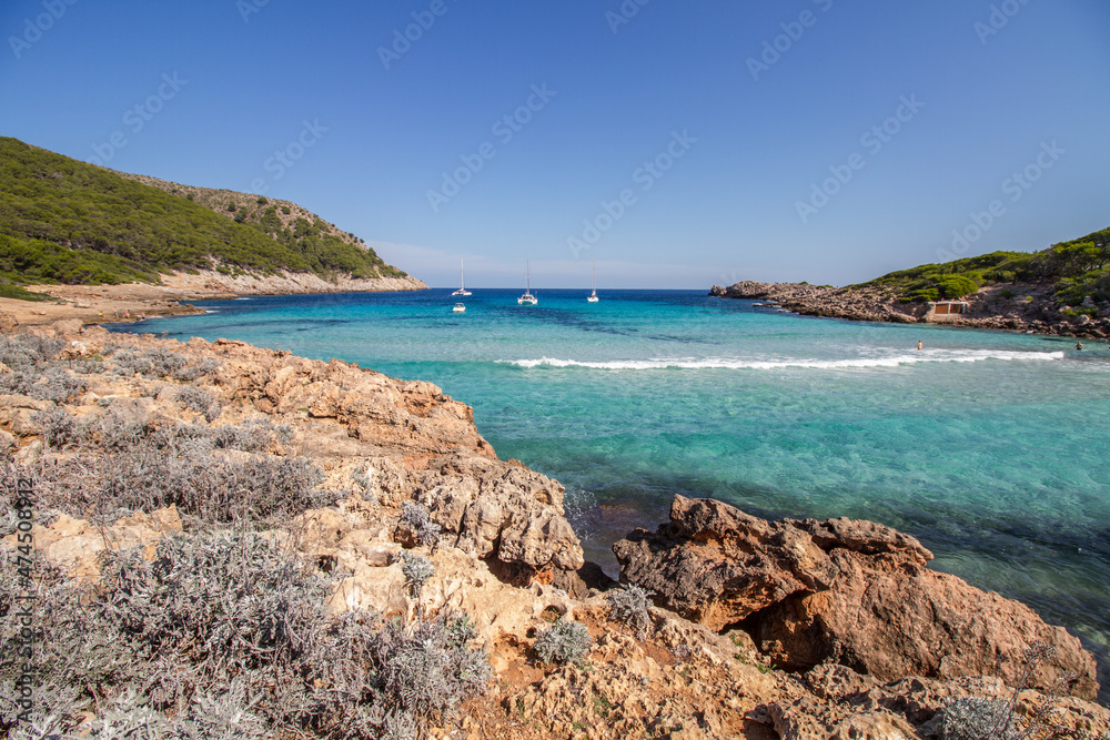 Turquoise water, rocky coast line and boats at beautiful bay Cala Moltó at Mallorca island, Mediterranean Sea, Spain