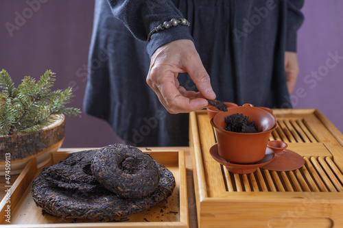 Making Puerh tea in a traditional style. Gaiwan tea bowl and puerh tea cakes on a wooden tea table.
