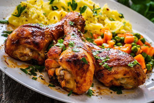 Barbecue chicken drumsticks with potato puree, grean peas and carrot on wooden table 