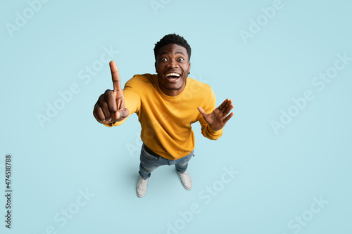 Top view of inspired african american guy pointing finger up