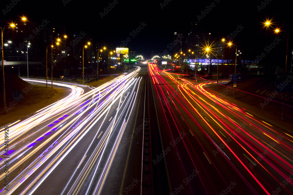 Light trails from fast moving cars at night. Cars move fast on a wide road
