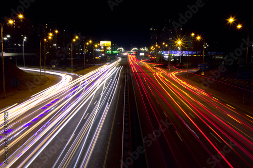 Light trails from fast moving cars at night. Cars move fast on a wide road