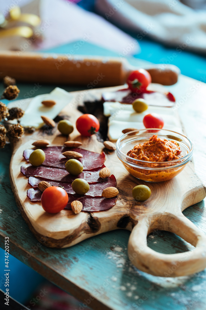 Fototapeta premium Fried dough called Ustipci with olives, paprika cream called ajvar and meat served on a wooden board. Bosnian or Serbian traditional food
