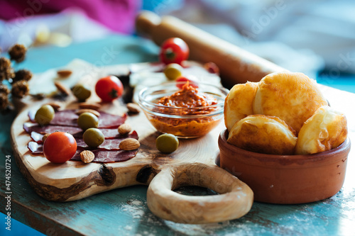Fried dough called Ustipci with olives, paprika cream called ajvar and meat served on a wooden board. Bosnian or Serbian traditional food photo