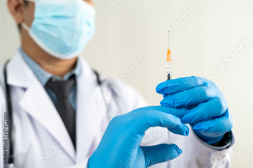 distant photo doctor wearing blue rubber gloves I am using a syringe. The idea is vaccination. Treatment is administered intravenously with a needle.