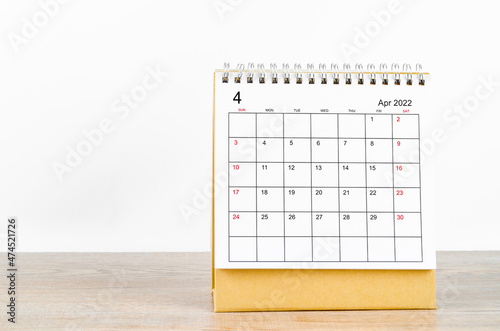 April 2022 desk calendar on wooden table.