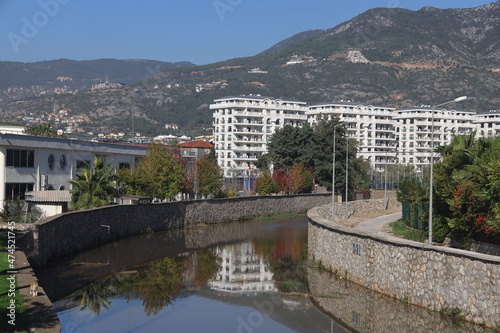 Stone embankment of the river against the background of residential buildings and mountains, Alanya, December 2021 photo