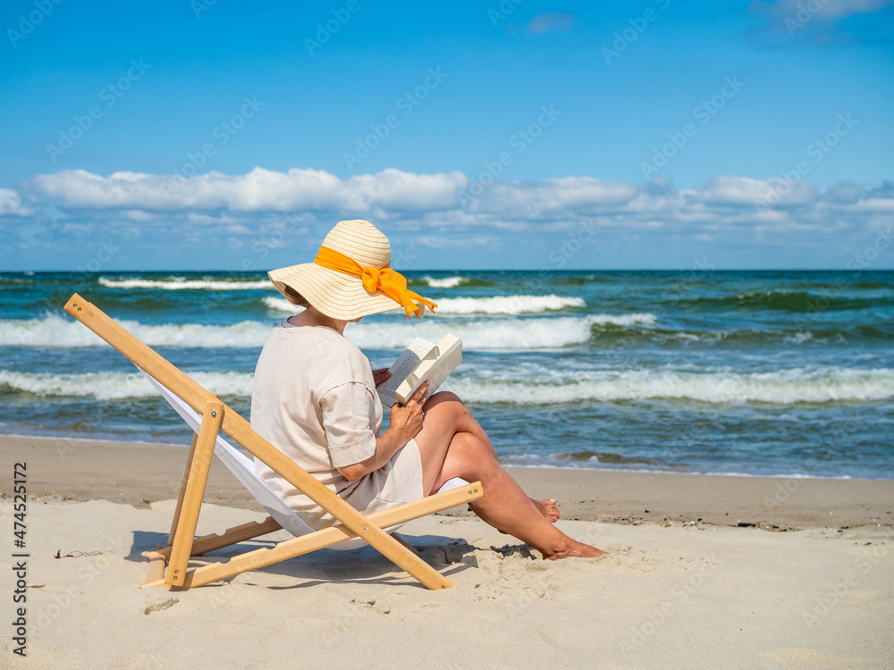 Woman relaxing on beach reading book sitting on sunbed
Woman relaxing on beach reading book sitting on sunbed