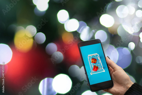 christmas shopping cart on phone on Christmas tree background,buying gifts online