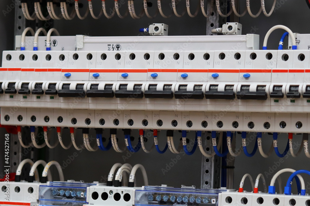 Electric circuit breakers with connected wires are installed in the electrical panel.