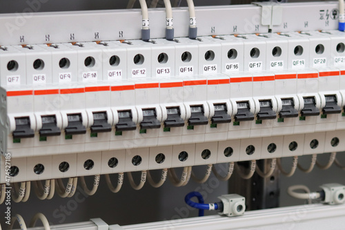 Electric circuit breakers with connected wires are installed in the electrical panel.
