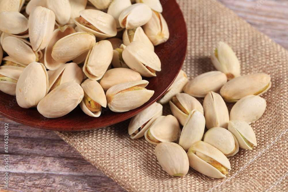 The pistachios are on the wooden board The pistachios are on the wooden board