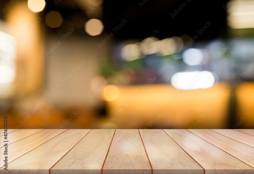 Empty wooden tabletop with lights bokeh on blur restaurant background.