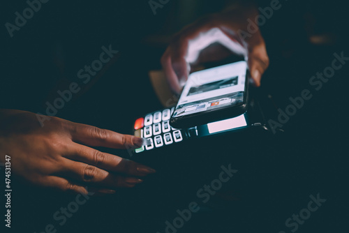 Contactless mobile payment. Payment terminal and smartphone in hands in bar photo