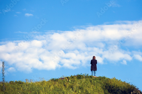 Girl on the hill looks into the distance into the clouds.