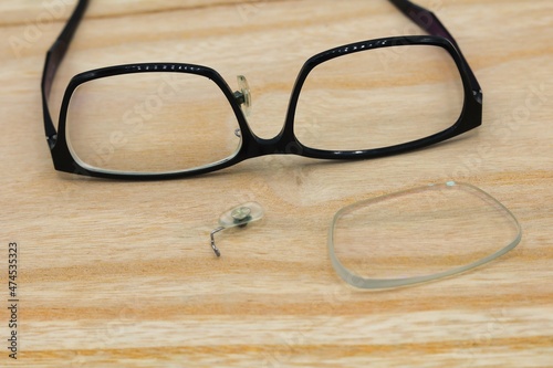 テーブルの上に置いてあるレンズと鼻あてが外れて壊れた眼鏡