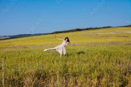 a beautiful woman in a summer dress walks across the field