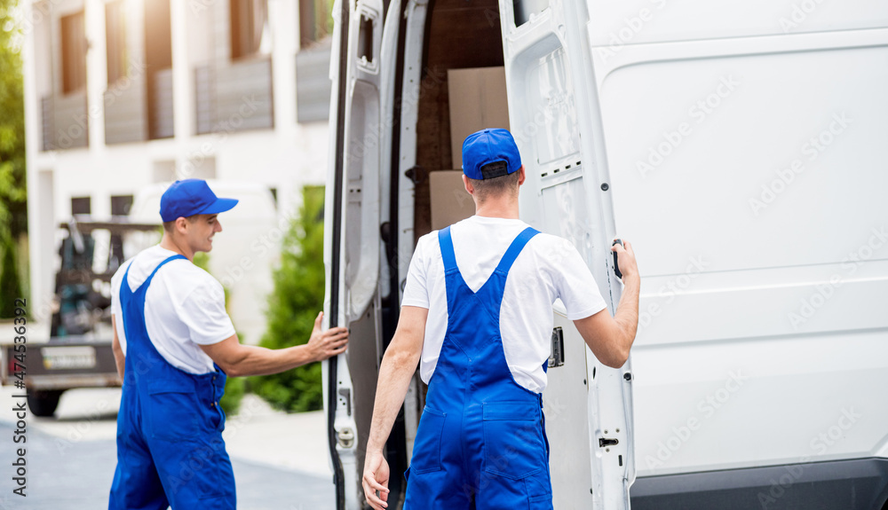 Two removal company workers unloading boxes from minibus into new home Two removal company workers unloading boxes from minibus into new home