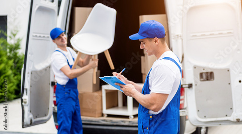 Two removal company workers unloading boxes from minibus into new home