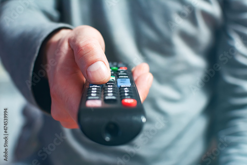 Man switches the TV channels.A hand with a remote control from the TV pointing directly at the camera.Selective focus