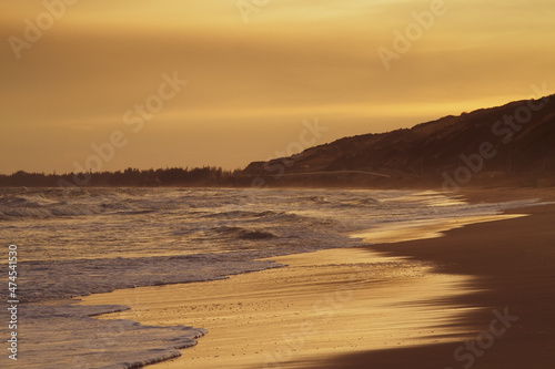 Empty beach of ocean beach at gold sunset.