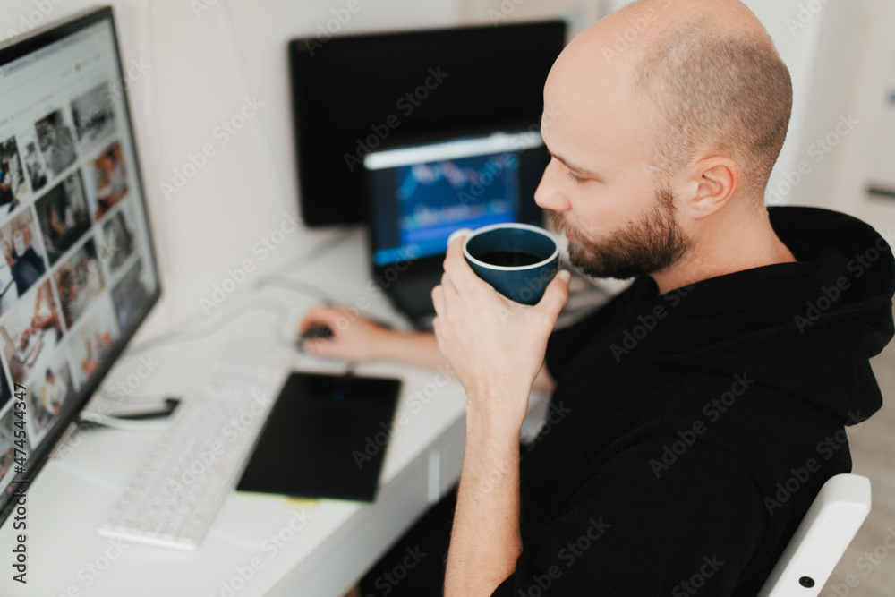 Obraz premium Millennial man working from home on computer and laptop