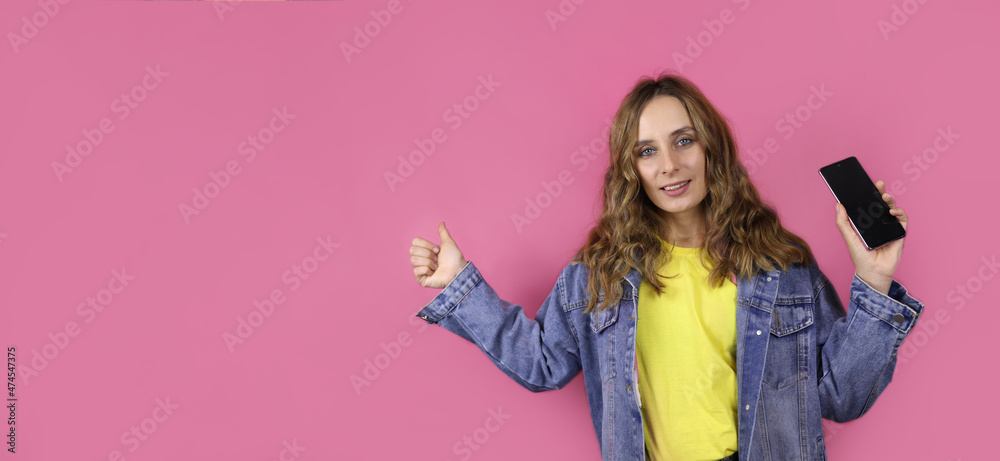 young woman holds a smartphone and points to a place for a text or product young woman holds a smartphone and points to a place for a text or product