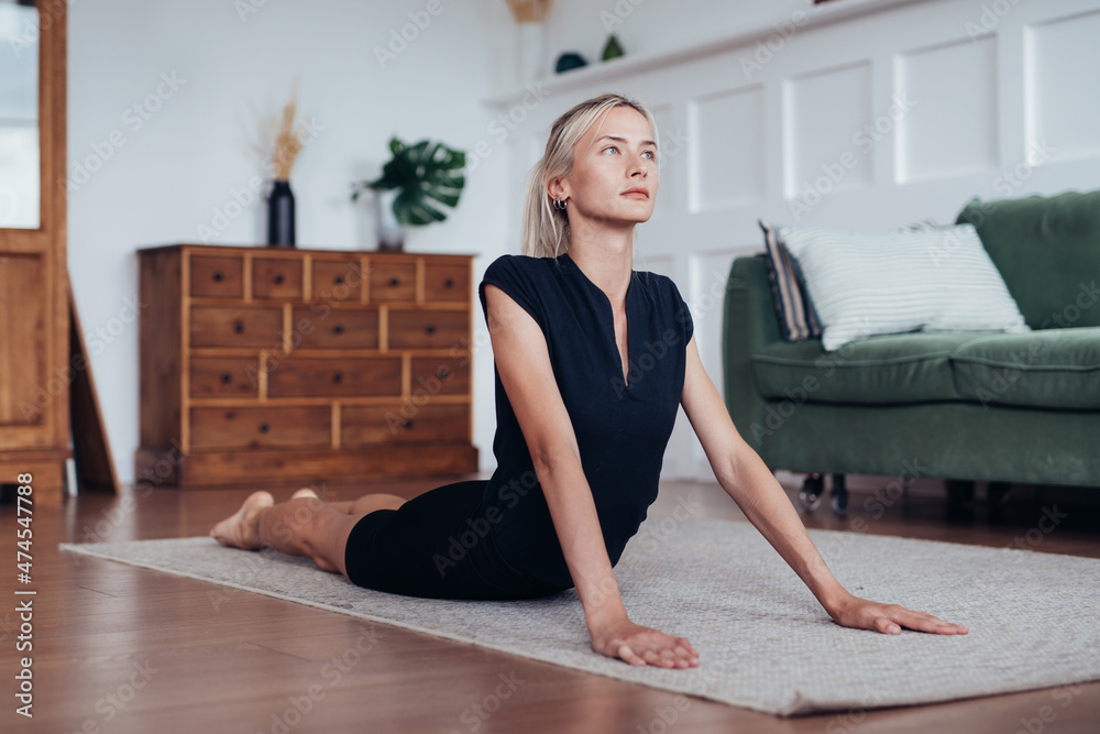 Young woman working out at home, lying on the floor and arching her back Young woman working out at home, lying on the floor and arching her back