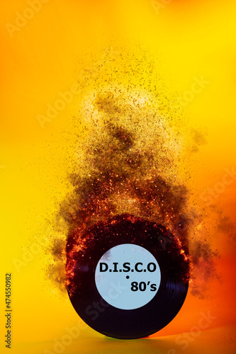 The concept of listening to music. Vintage vinyl record with the inscription DISCO on fire. photo on a yellow background.