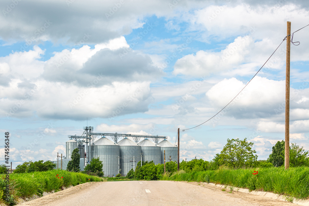 Obraz premium Road to Silos on a beautiful day with puffy clouds and fresh green grass