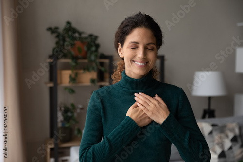 Papier peint Smiling young Hispanic woman hold hands at heart chest feel grateful and thankful