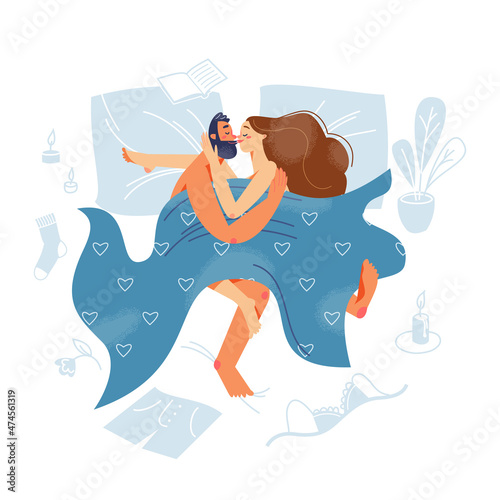 Couple of lovers laying in bed together, woman and man hugging, clothes scattered around